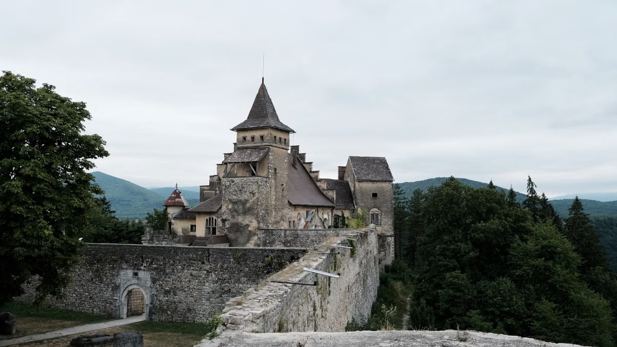 Explore the medieval Ostrozac Castle, nestled among lush hills, with its fortified walls and towers.